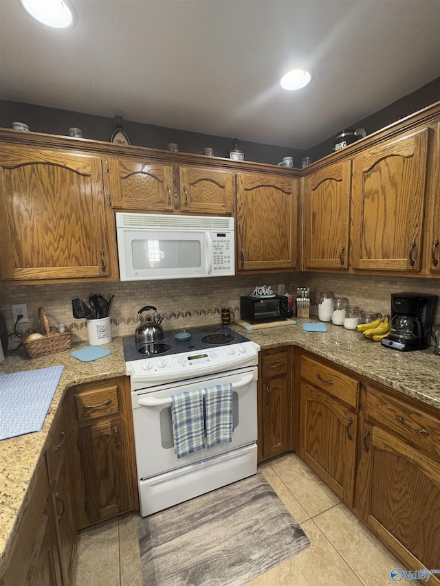 kitchen with light stone countertops, white appliances, and decorative backsplash