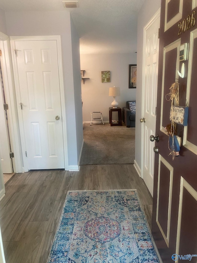 hall featuring visible vents, baseboards, and wood finished floors