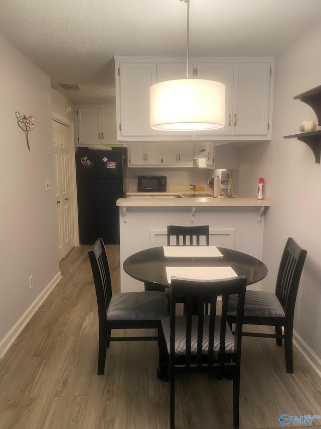 dining room with baseboards, visible vents, and wood finished floors