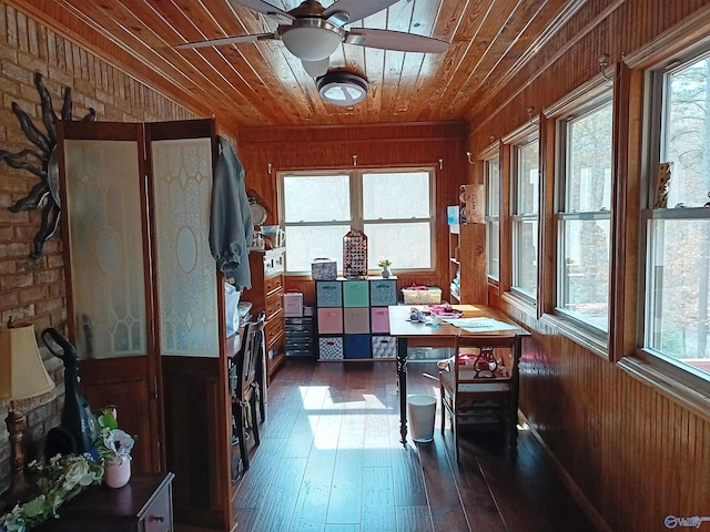 dining room featuring wood ceiling, ceiling fan, wooden walls, and dark wood-type flooring