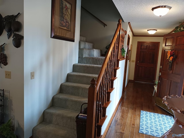 stairway featuring hardwood / wood-style floors, crown molding, and a textured ceiling