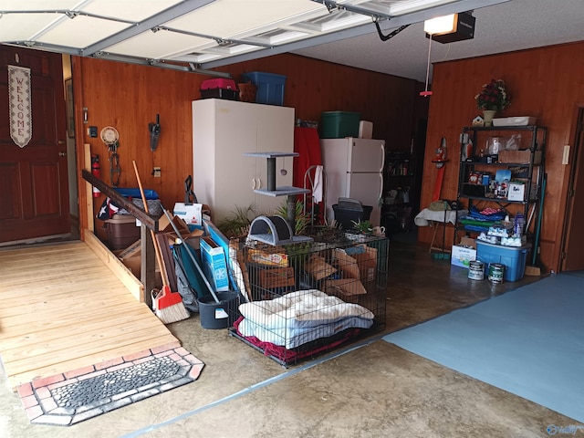 garage featuring a garage door opener, wooden walls, and white fridge