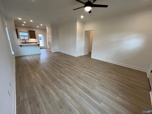 unfurnished living room featuring ceiling fan, light wood-type flooring, and crown molding