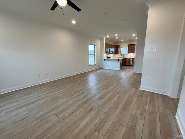 unfurnished living room with light hardwood / wood-style floors, ceiling fan, crown molding, and sink