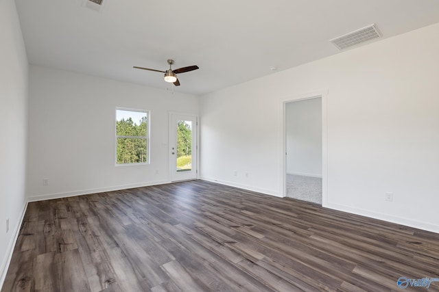 spare room with dark wood-style floors, ceiling fan, visible vents, and baseboards