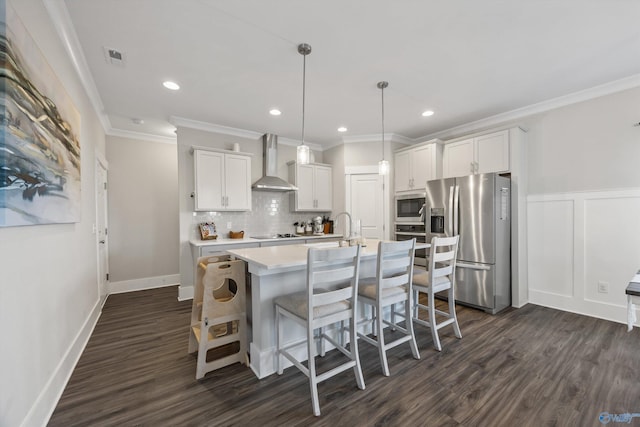 kitchen with stainless steel appliances, pendant lighting, white cabinetry, and wall chimney range hood