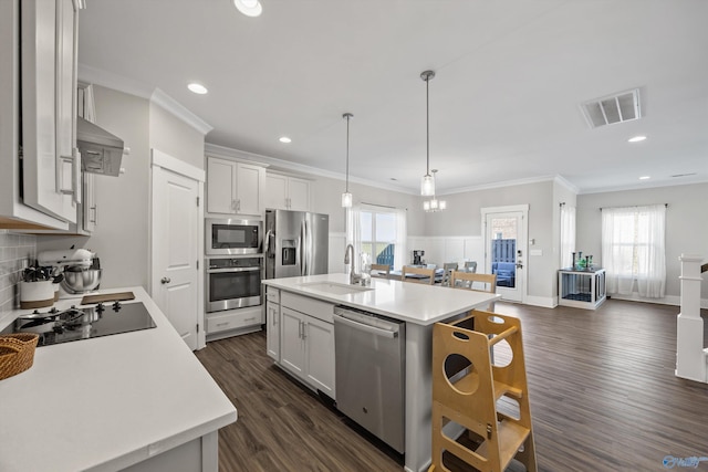 kitchen featuring decorative light fixtures, a center island with sink, light countertops, visible vents, and appliances with stainless steel finishes