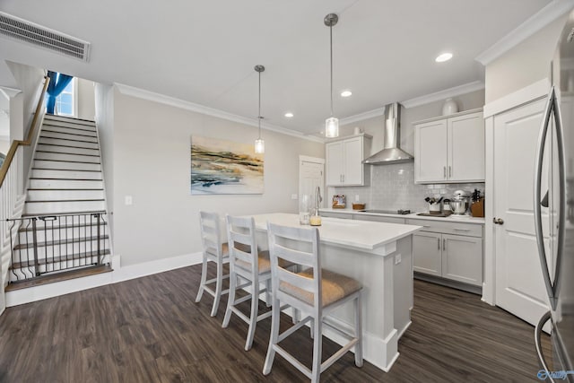 kitchen featuring a kitchen island with sink, visible vents, white cabinets, light countertops, and wall chimney exhaust hood