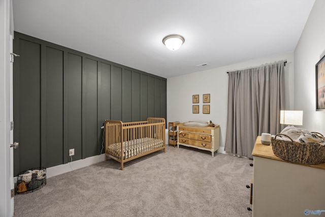 bedroom with a nursery area, light carpet, and visible vents