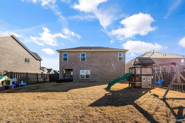 back of house with a playground, brick siding, and a fenced backyard