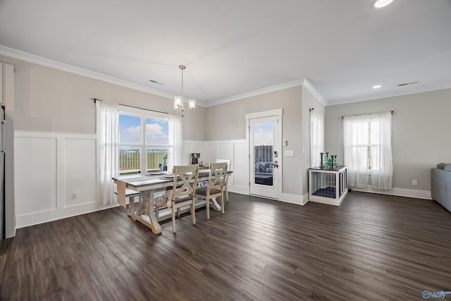 dining space featuring a notable chandelier, dark wood finished floors, crown molding, and a decorative wall