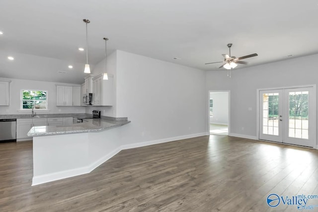 kitchen featuring stainless steel appliances, white cabinets, wood finished floors, a peninsula, and baseboards