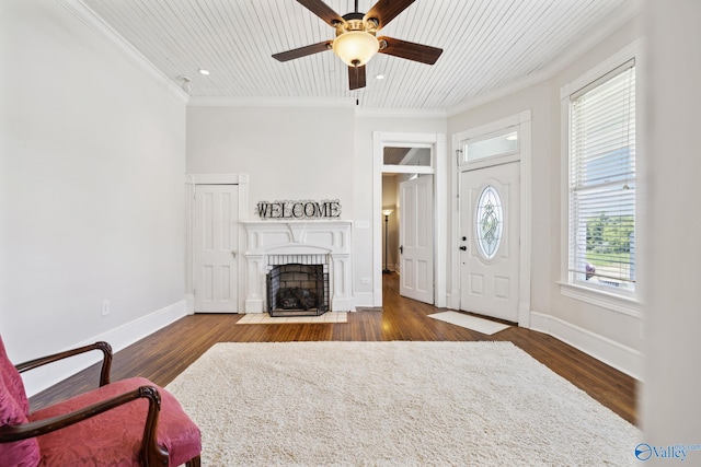 living room featuring a healthy amount of sunlight, ceiling fan, crown molding, and dark wood-type flooring