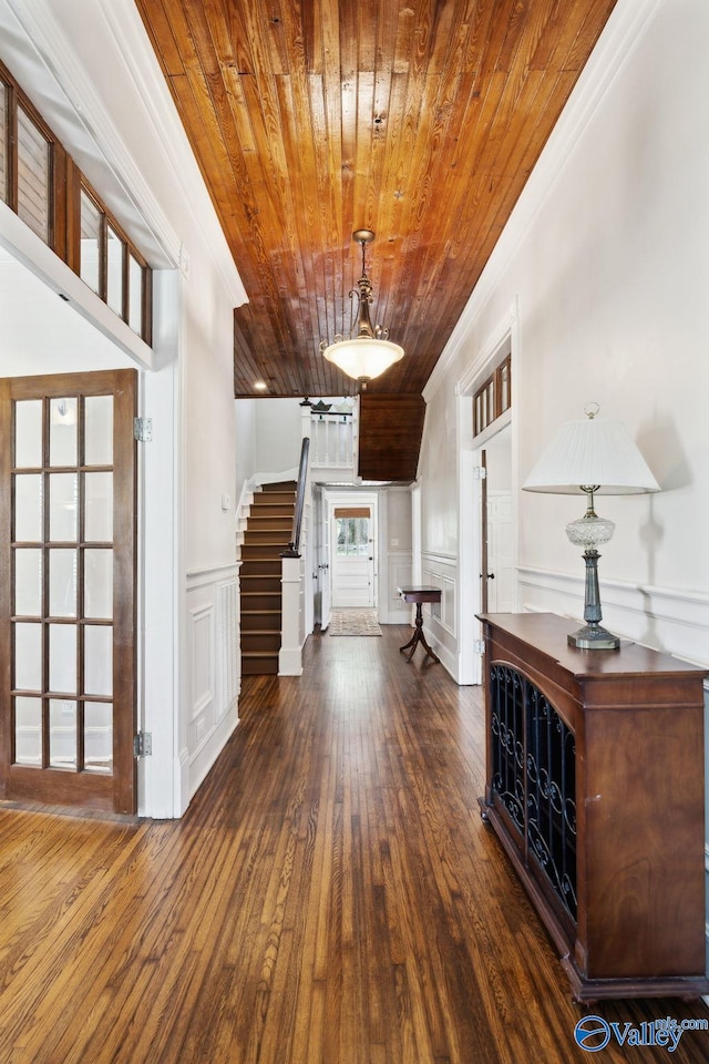 foyer entrance with dark hardwood / wood-style floors, ornamental molding, and wood ceiling