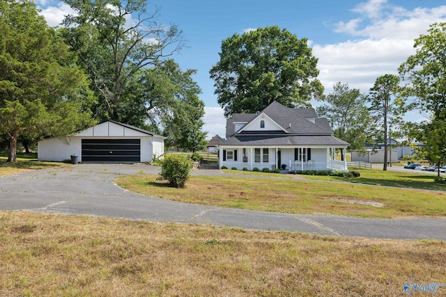 view of front of property featuring a garage, covered porch, an outdoor structure, and a front lawn