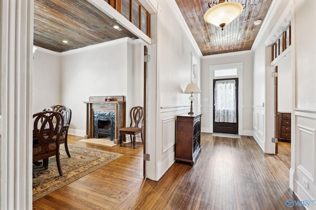 entryway featuring hardwood / wood-style flooring, a fireplace, wood ceiling, and ornamental molding