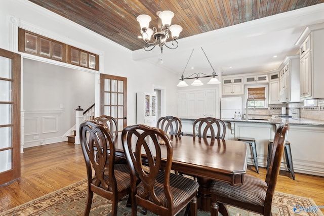 dining space with french doors, wood ceiling, sink, an inviting chandelier, and light hardwood / wood-style floors