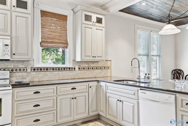 kitchen with kitchen peninsula, white appliances, dark stone counters, and sink