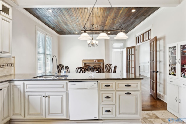 kitchen featuring backsplash, white dishwasher, sink, hanging light fixtures, and a chandelier