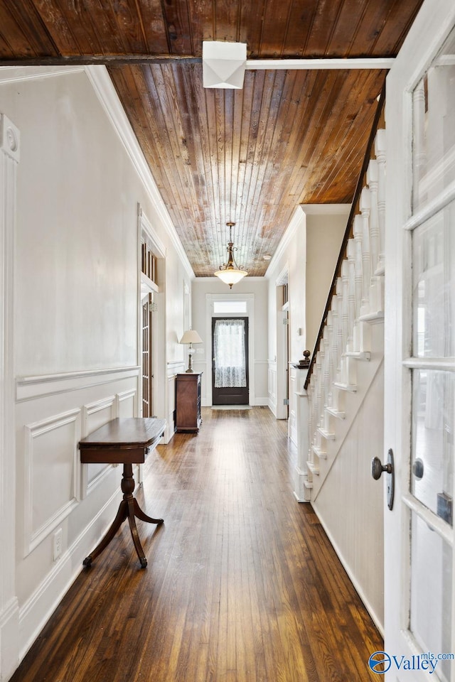 foyer with dark hardwood / wood-style floors, wooden ceiling, and ornamental molding