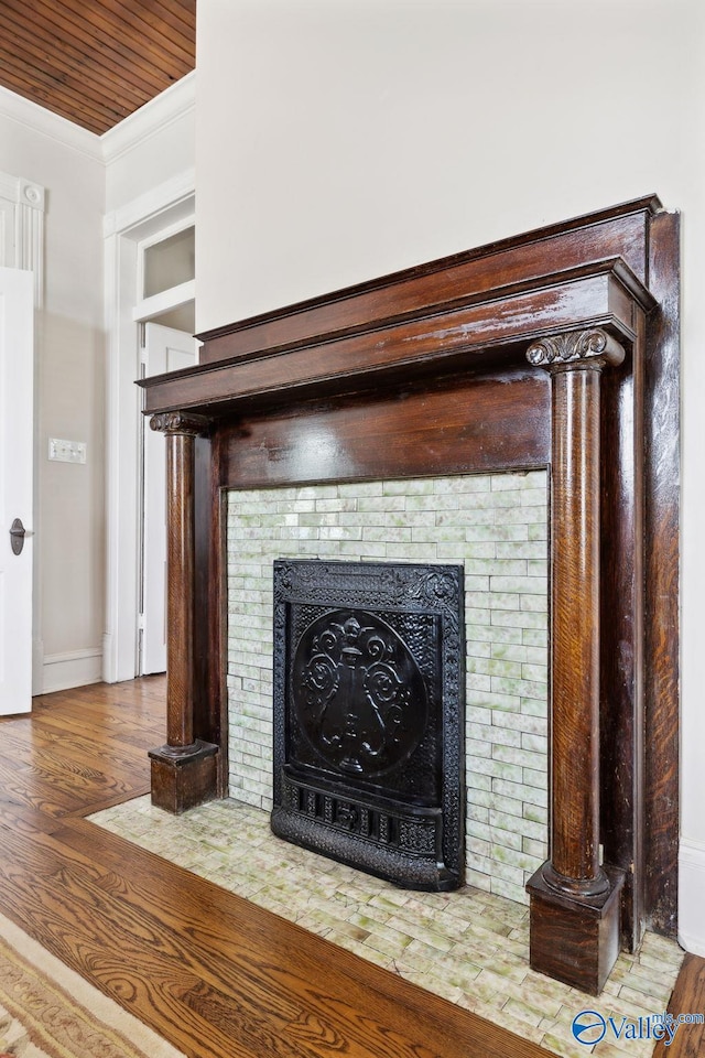 room details featuring a tile fireplace, crown molding, and hardwood / wood-style floors