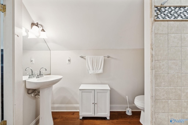 bathroom featuring hardwood / wood-style floors, toilet, lofted ceiling, and sink