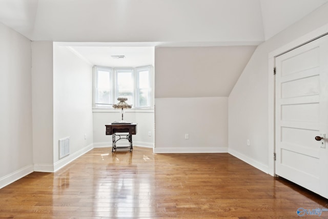 additional living space with hardwood / wood-style flooring and vaulted ceiling