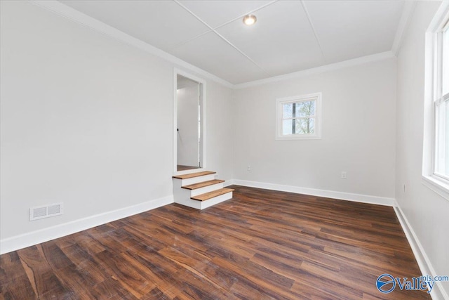 spare room featuring dark wood-type flooring, a healthy amount of sunlight, and ornamental molding