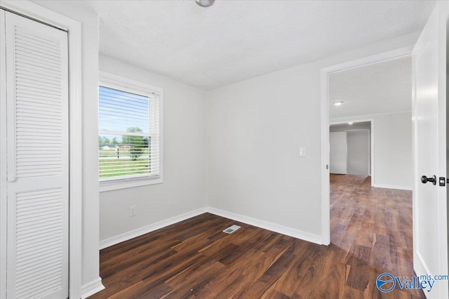 spare room featuring dark hardwood / wood-style flooring and a textured ceiling