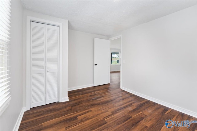 unfurnished bedroom with dark wood-type flooring, a textured ceiling, and a closet