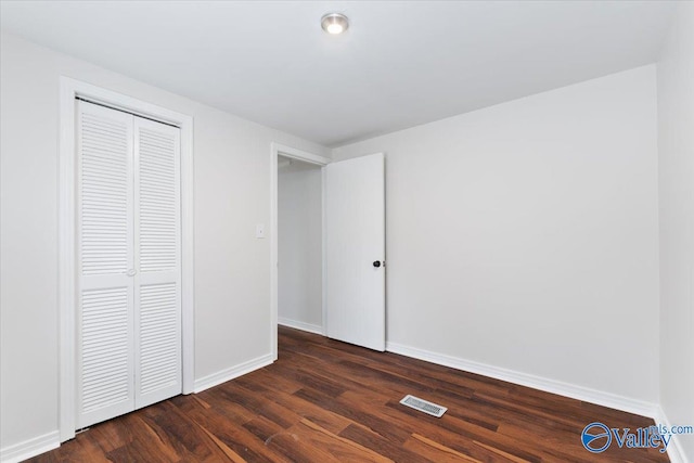 unfurnished bedroom with dark wood-type flooring and a closet