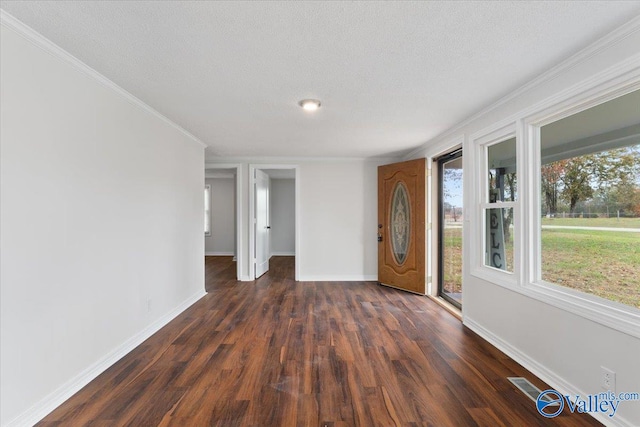 empty room with dark hardwood / wood-style flooring, a textured ceiling, and plenty of natural light