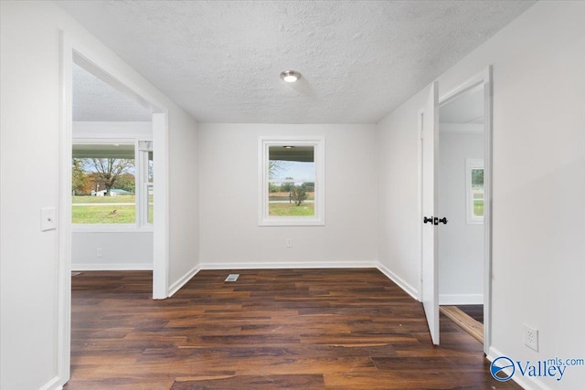 unfurnished room featuring dark wood-type flooring and a textured ceiling