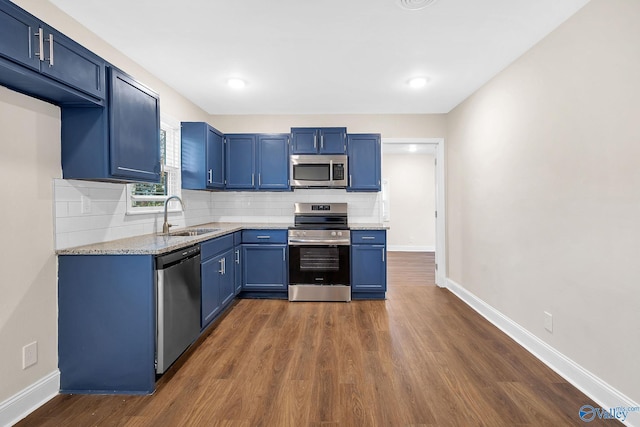 kitchen with a sink, decorative backsplash, blue cabinetry, and stainless steel appliances