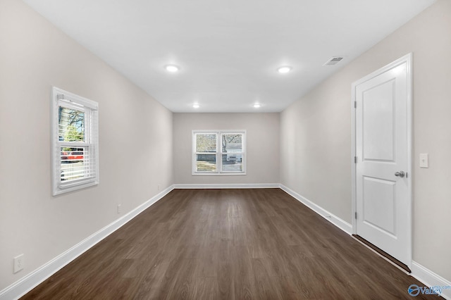 empty room with visible vents, baseboards, and dark wood-style floors