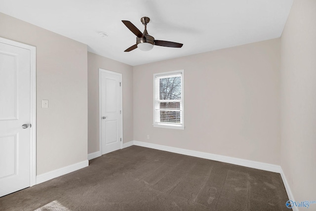 unfurnished bedroom with baseboards, dark colored carpet, and ceiling fan