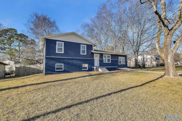 tri-level home featuring a front yard and fence