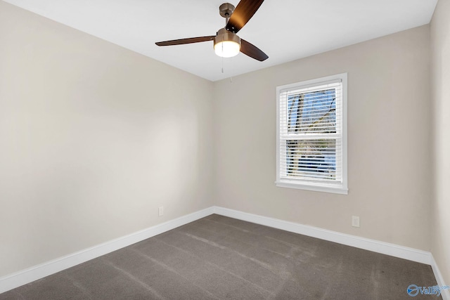 spare room featuring baseboards, dark colored carpet, and ceiling fan