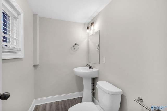 half bath featuring toilet, wood finished floors, and baseboards