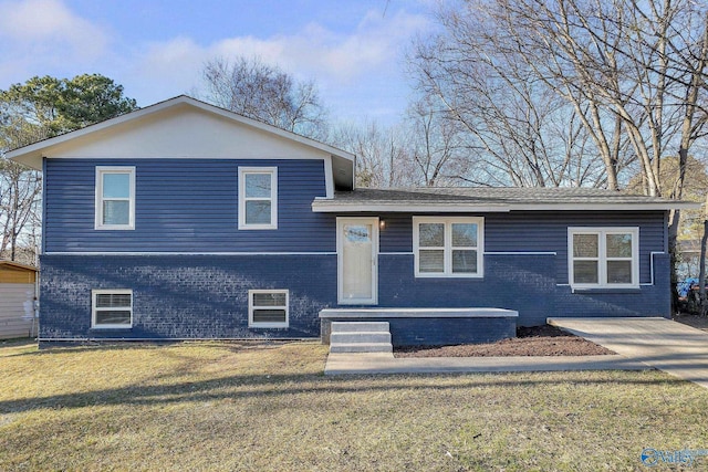 split level home featuring a front lawn and brick siding