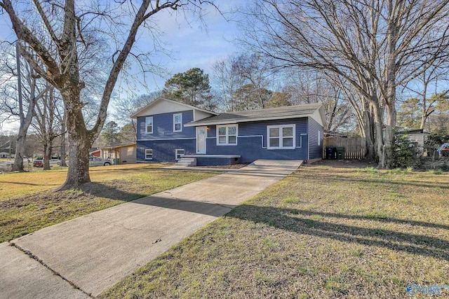 split level home featuring a front yard, concrete driveway, and fence