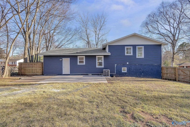 back of property with central AC unit, a yard, and fence