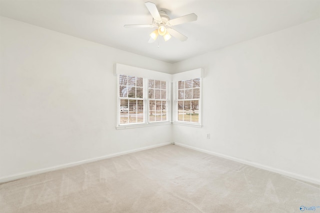 unfurnished room with a ceiling fan, baseboards, and light carpet