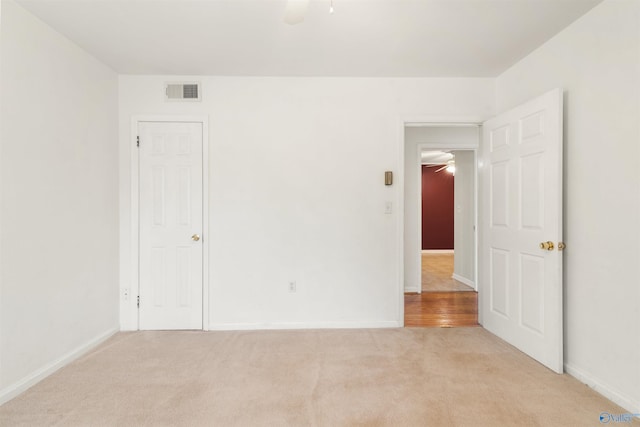 unfurnished bedroom with visible vents, light colored carpet, and baseboards