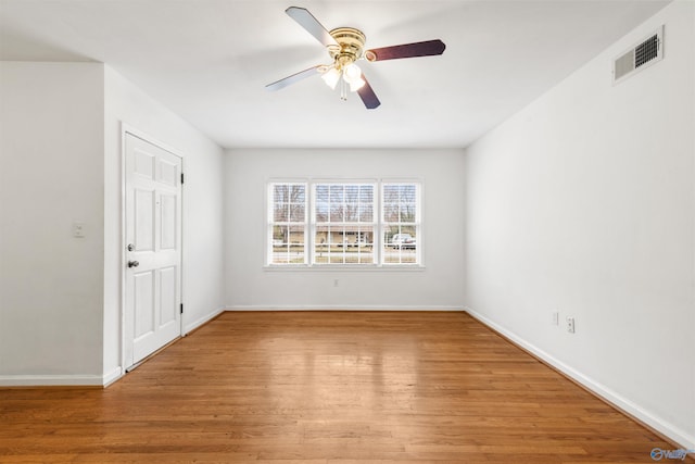 spare room with baseboards, wood finished floors, visible vents, and ceiling fan