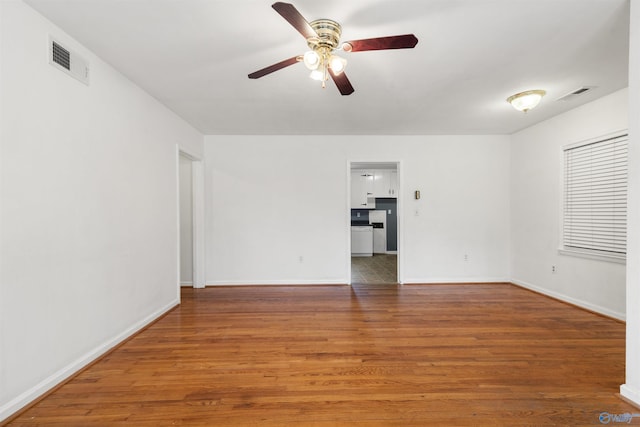 empty room with visible vents, baseboards, ceiling fan, and wood finished floors