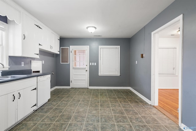 kitchen with a sink, dark countertops, white cabinetry, baseboards, and dishwasher