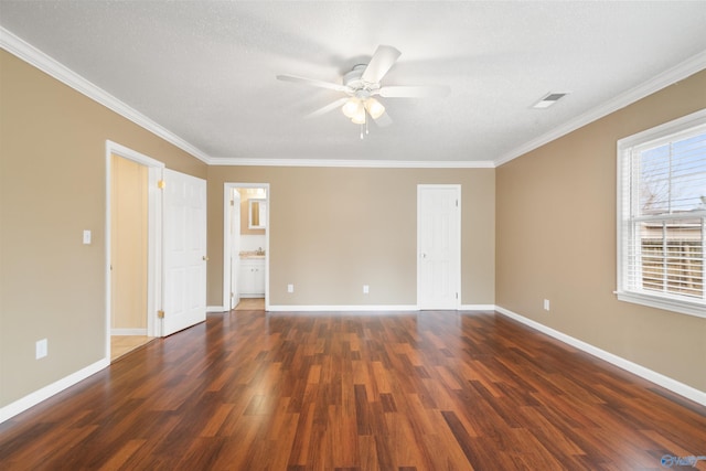 empty room with dark wood-type flooring, crown molding, and baseboards