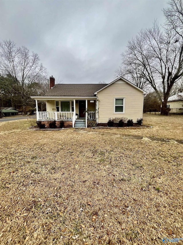 ranch-style home featuring covered porch and a front lawn