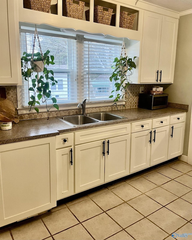 kitchen featuring light tile patterned flooring, sink, white cabinetry, a wealth of natural light, and decorative backsplash